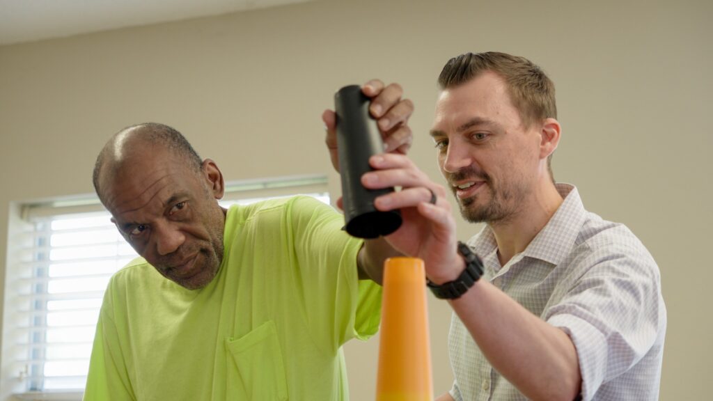 A man doing short term rehab therapy is assisted by a trainer