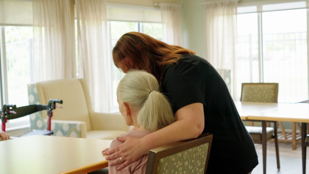 A nurse hugs a resident at a skilled nursing facility